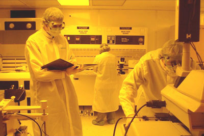 Graduate and undergraduate students work together processing devices inside the clean room.