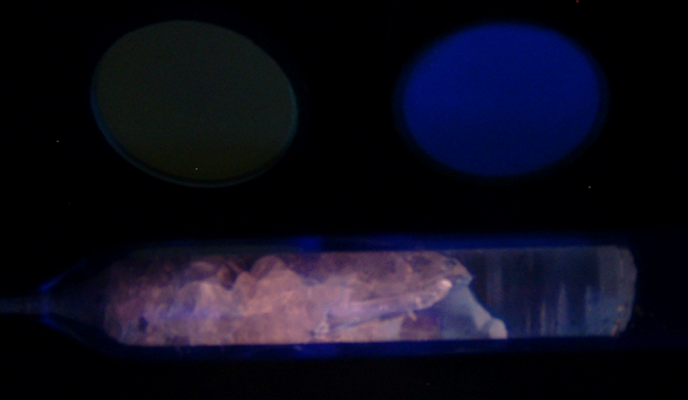 This LaBr3 crystal was grown in the SMART Lab by a low pressure vertical Bridgman technique, and is shown under ultraviolet light. The Ingot is 19 mm in diameter. Much of the ingot cracked during cooling, yet there is a 37 mm long single crystal at the tail end. For comparison, a NaI(Tl) commercial cystal is shown in the upper right. 