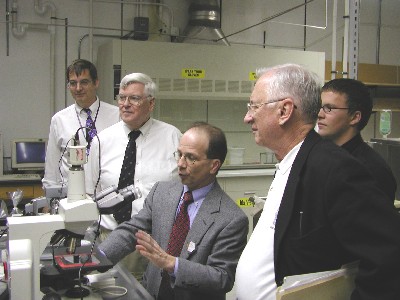 Mike Whaley, Dr. Shultis, Dr. Foulkes, and Troy Unruh look on as Dr. McGregor demonstrates an infrared microscope. 